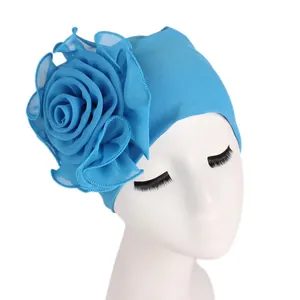 Detail of the bright blue floral turban featuring a large 3D layered rose decoration