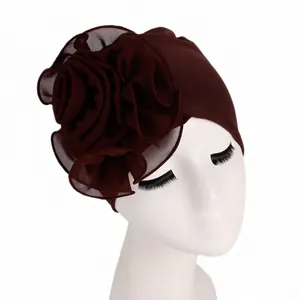Detailed close-up of dark brown stretch turban with a large side flower on a display head