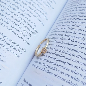 Close-up of a matte gold S925 silver square ring on vintage book pages for retro style