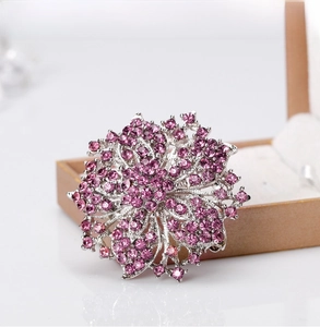 Detailed view of luxury flower brooch with purple rhinestones on a gold jewelry box