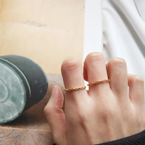 Detail of twisted rope and chain link 18k gold plated silver rings on finger