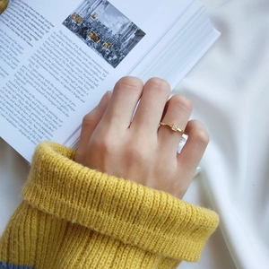 Detailed view of simple gold ring with square crystal on an open art book background