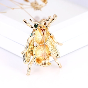 Exquisite gold bee brooch with enamel accents and rhinestone details shown on white background