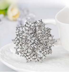 Macro detail of luxury crystal flower brooch pinned on a white ceramic cup edge