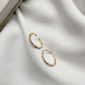 Detailed view of two gold wavy textured adjustable rings on white silk background
