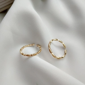 Macro shot of gold-plated adjustable rings with beaded and twisted rope textures on silk