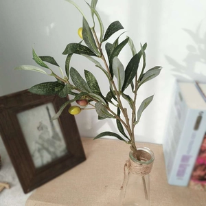 Artificial olive branch with green leaves and fruits in a glass bottle for home decor