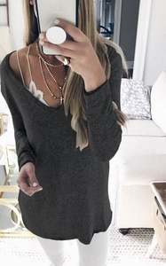 Detail of dark charcoal grey V-neck knit sweater styled with layered necklaces
