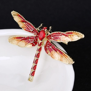 Macro detail of red enamel dragonfly brooch with gold alloy base and faceted crystal