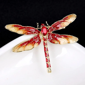 Macro detail of enamel dragonfly brooch with red gemstone and gold gradient wings