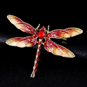 Macro detail of red and beige enamel dragonfly brooch with sparkling crystals