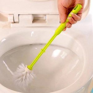 Green plastic toilet brush with white bristles cleaning the inside of a white toilet bowl
