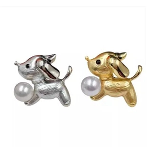 Close-up of dog-shaped brooches in gold and silver finish with white pearls