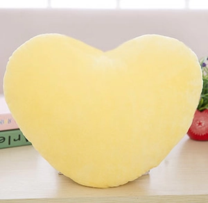 Dettaglio macro del morbido cuscino a forma di cuore giallo su superficie di legno