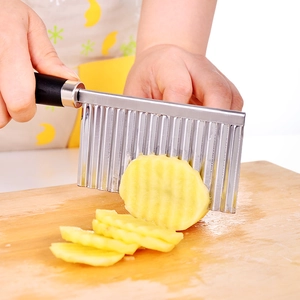 Schneiden von Kartoffeln auf einem Holzbrett mit einem Wellenschneider aus Edelstahl und Griff