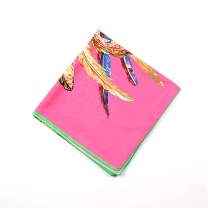 Détail de l'imprimé plumes colorées sur un foulard en soie rose avec bordure verte