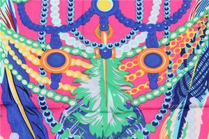 Vue macro de motifs de plumes et couronnes sur un foulard carré en satin rose vif