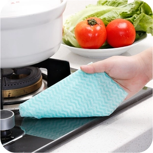 Disposable blue wave non-woven cleaning cloth wiping a kitchen stove countertop