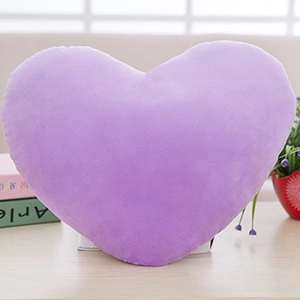 Dettaglio del morbido cuscino a cuore in peluche viola con texture vellutata e cuciture