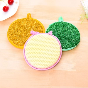 Three-piece set of gold and green metallic scourers and yellow sponge on wooden background