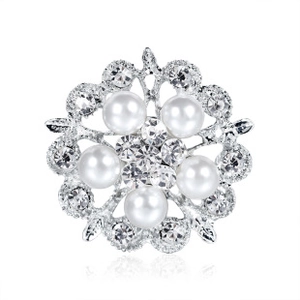 Macro shot of silver metal flower brooch featuring white pearls and clear crystals