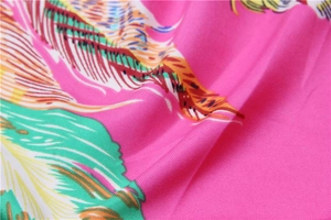 Détail macro d'un foulard en soie avec motifs plumes colorés sur fond rose fuchsia