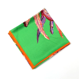 Détail macro d'un foulard en soie aux motifs de plumes colorées et bordure orange