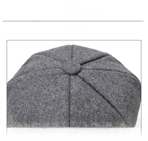 Close-up of top stitching and button detail on grey wool octagonal newsboy cap