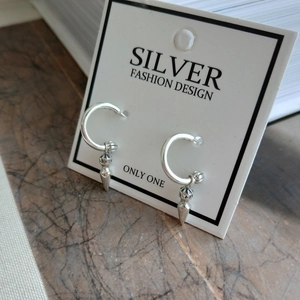 Close-up of S925 sterling silver drop earrings with hoop and spike design on card