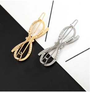 Macro detail of infinity knot hair clips with brushed metal texture in gold and silver