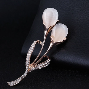 Macro shot of rose gold flower brooch with white cat-eye stones and sparkling crystals