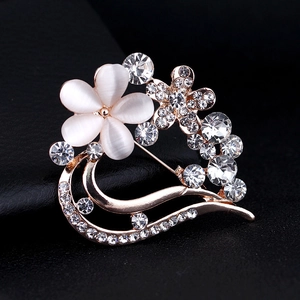 Macro detail of golden flower brooch featuring white cat eye stones and sparkling rhinestones