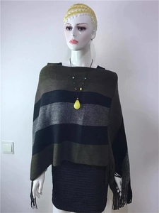 Detailed view of women's knitted striped poncho with fringes in green and black
