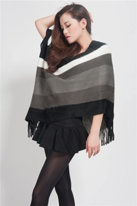 Detail of black and white gradient striped knit poncho with fringe trim on female model