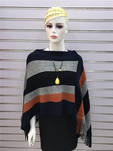 Detailed view of striped knit poncho with fringe trim and navy blue horizontal patterns
