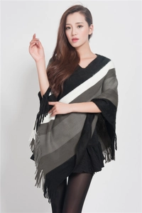 Detail of grey striped knitted poncho with tassel fringe trim for women's winter fashion