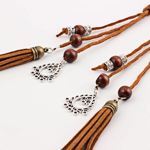 Handmade brown tassel waist chain with wooden beads and silver metal pendants on white background