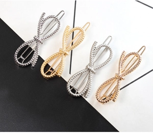 Macro detail of bow-shaped hair clips with twisted rope texture in various metallic finishes