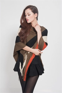Close-up of knit poncho with brown and red plaid pattern and fringe detail edges