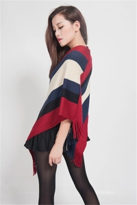 Detail of color-block striped knit poncho sweater featuring fringe hem and tassel trim