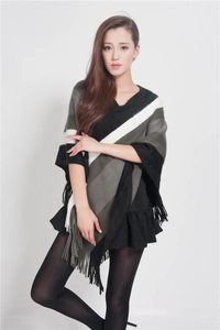 Full view of a knit striped poncho with fringe detail on a model in a white studio