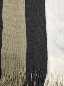 Close-up of the knitted striped texture and delicate tassel hem detail on the shawl