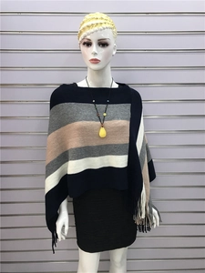 Detail of multi-color striped knit poncho featuring fringe hem and soft fabric texture