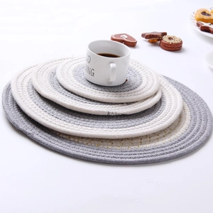 Detail of nested round cotton woven placemats in grey and cream with gold accents