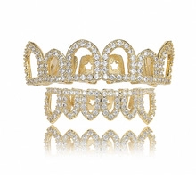 Close-up of gold hip hop teeth grillz set with sparkling zircons and star patterns