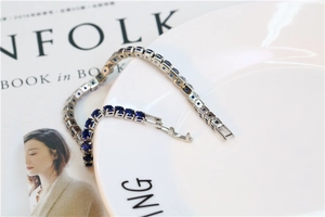 Close-up of blue zircon tennis bracelet on a white ceramic plate with magazine