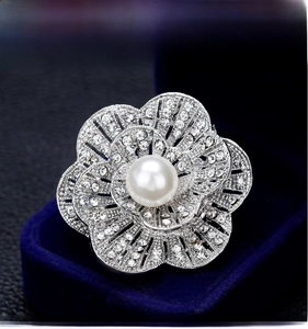 Detailed macro view of camellia brooch featuring central pearl and sparkling rhinestones