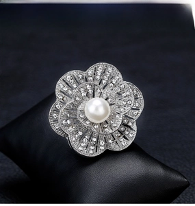 Macro detail of silver floral brooch with white pearl and sparkling crystals on leather
