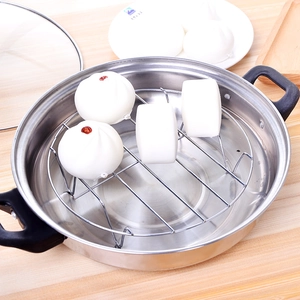 Stainless steel steamer rack in a pot with steamed buns on a wooden table