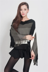Detail of multi-color striped knit poncho with fringe edges and soft texture fabric